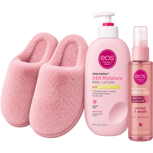 A pair of pink furry closed toe slippers with a bottle of pink eos lotion and a bottle of sheer pink shimmer coconut and vanilla body oil